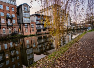 Norwich, Norfolk, İngiltere - 29 Aralık 2019. Norwich şehrindeki Wensum Nehri 'nin yanındaki bir yolun ve pahalı deniz kenarındaki dairelerin, dairelerin ve çatı katlarının resimli bir fotoğrafı.