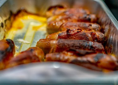 Seçici odak noktası ve sosisleri battaniyeye sarmak, sosisi pastırmaya sarmak, alüminyum folyo tepsisine sarmak.