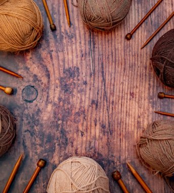 Kahverengi iplik yumakları ve ahşap bir zeminde bambu örgü iğneleri.