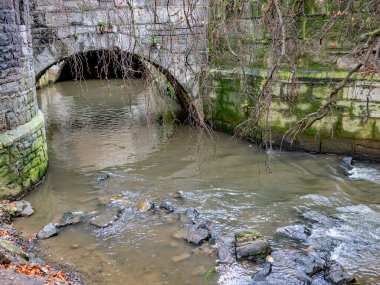 Hollanda 'nın Maastricht kasabasında hızlı akan kayalık nehir ve antik taş köprü