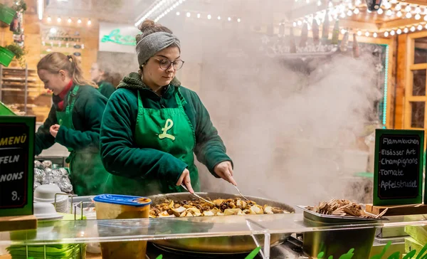 Aachen, Almanya - 07 Aralık 2019. Aachen, Almanya 'daki 2019 Noel pazarında baharatlı şampiyonları (mantar) kızartan bir kadın şefin resimli resmi.