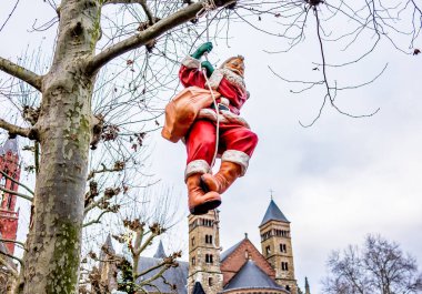 Maastricht, Hollanda - Aralık 07 2019. Hollanda, Maastricht 'teki 2019 Noel pazarındaki bir ağaç dalına asılı duran Noel Baba' nın illüstrasyon fotoğrafı.