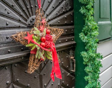 Monschau, Almanya - 08 Aralık 2019. Almanya 'nın Monschau kentindeki festival döneminde kimliği belirsiz bir mülkün kapısında asılı geleneksel bir Alman çelenginin resimli bir resmi.