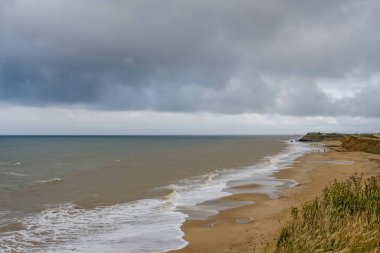 Fırtınalı bir akşamda Norfolk sahilindeki Happisburgh plajına bakın.