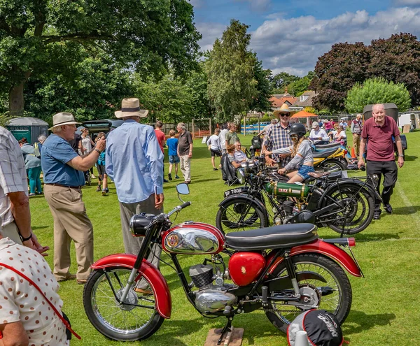Wroxham, Norfolk, İngiltere - 21 Temmuz 2019. Klasik araba şovu katılımcılarının Wroxham 'daki geleneksel klasik ve klasik otomobil fuarında klasik ve klasik motosiklet koleksiyonuna baktıkları bir illüstrasyon fotoğrafı.