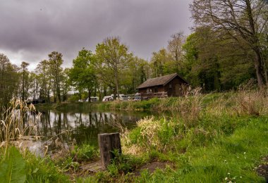 Gri ve bulutlu bir hafta sonu tatilinde, Norfolk kırsalında eski bir balıkçı kulübesinin yanında küçük bir kamp yeri, ahşap balıkçı kulübesi.