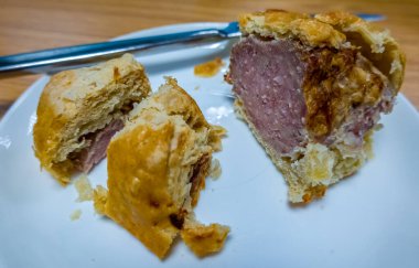 Tahta bir masada beyaz bir tabakta kesilmiş sosisli böreğe odaklan.