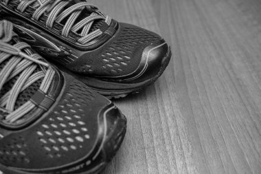 Ahşap zeminde çalışan siyah ve renkli spor ayakkabıları kapatın.