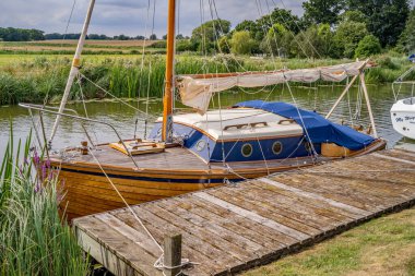 Boynuz, Norfolk, İngiltere - 03 Ağustos 2019. Geleneksel ahşap yelkenli teknesinin Norfolk Hatunları 'ndaki Bure Nehri' ndeki ahşap rıhtıma bağlanmış resmi.