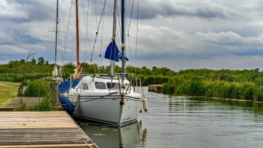 Boynuz, Norfolk, İngiltere - 03 Ağustos 2019. Bure, Horning, Norfolk Broads nehrinin kenarında demirlemiş küçük bir lezbiyen yelkenli teknesinin resimli.