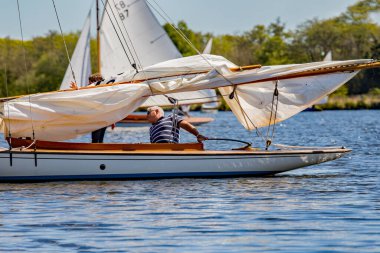 Wroxham, Norfolk, İngiltere - 12 Mayıs 2019. Wroxham Broad, Norfolk 'ta yelkenli yarışı galası. Erkek denizci telaşlı bir yarıştan sonra kahverengi teknesini dikkatle iskeleye doğru sürüyor..