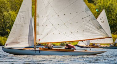 Wroxham, Norfolk, İngiltere - 12 Mayıs 2019. Wroxham Broad, Norfolk 'taki yelkenli yarışı galasının editör fotoğrafı. Erkek bir denizci Norfolk Hatunları 'nda çılgın bir yarış sırasında kahverengi teknesinin etrafında dolanıyor. 