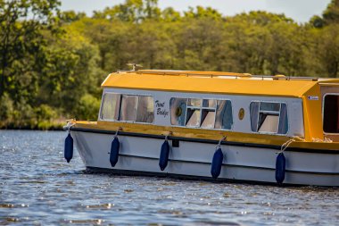 Wroxham, Norfolk, İngiltere - 12 Mayıs 2019. Richardsonlar 'daki turistlerin bir editör fotoğrafı Wroxham Broad' da tekne sürüşü yapıyor. Açık ve güneşli bir günde yelkenli tekne yarışları arasında.