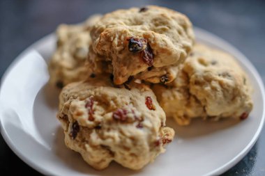 Ev yapımı ve ev yapımı meyveli çörekleri küçük beyaz bir tabakta kasten yakın ve seçici bir şekilde Bokeh 'e odakla.