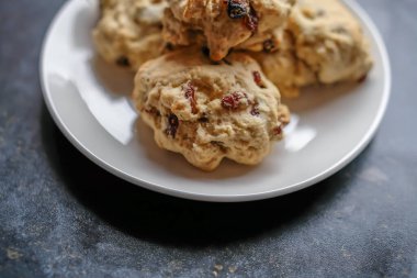 Ev yapımı ve ev yapımı meyveli çörekleri küçük beyaz bir tabakta kasten yakın ve seçici bir şekilde Bokeh 'e odakla.