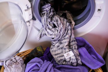 Çamaşır makinesinden yeni çıkarılmış giysiler ve çamaşır sepetine konmuş.