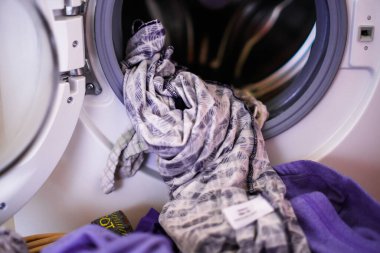 Çamaşır makinesinden yeni çıkarılmış giysiler ve çamaşır sepetine konmuş.