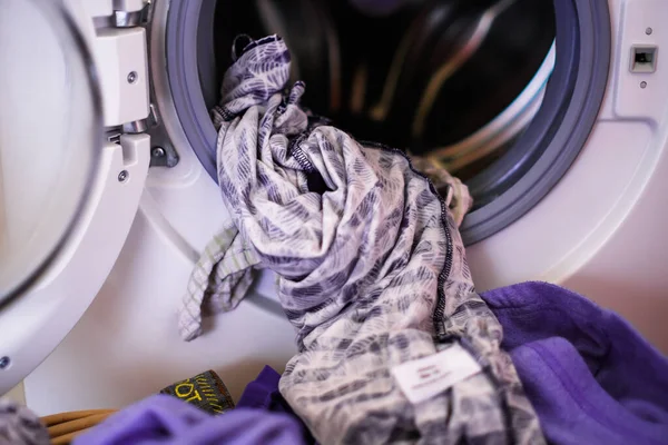 Çamaşır makinesinden yeni çıkarılmış giysiler ve çamaşır sepetine konmuş.