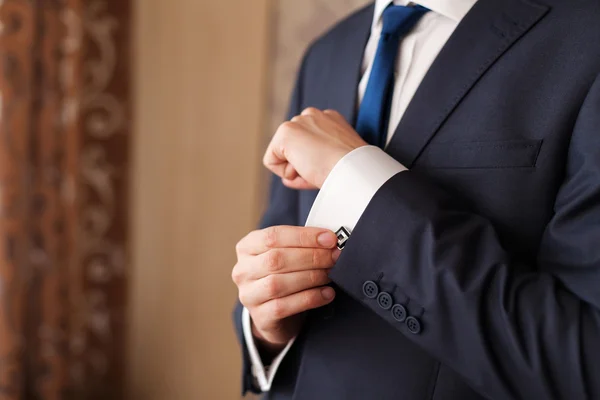 Closeup of a man in black suit correcting a sleeve — Stock Photo, Image