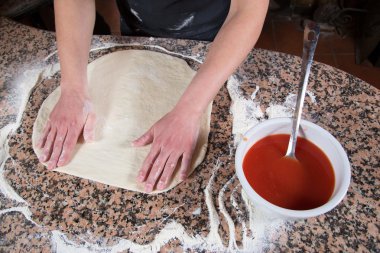 Woman Hands On Dough Pizza Base With Tomato Sauce On Marble Table