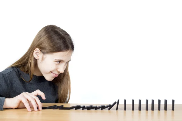 Πλευρική όψη του χαμογελαστή κορίτσι προώθηση ντόμινο σε ξύλινο σανίδα απομονωμένη σε λευκό — Φωτογραφία Αρχείου
