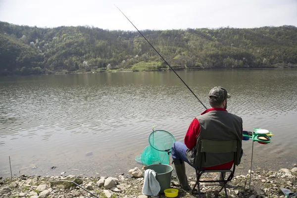 Pêcheur avec son dos vers la caméra assis sur la côte de la rivière Profitant de la pêche à la ligne et belle nature — Photo