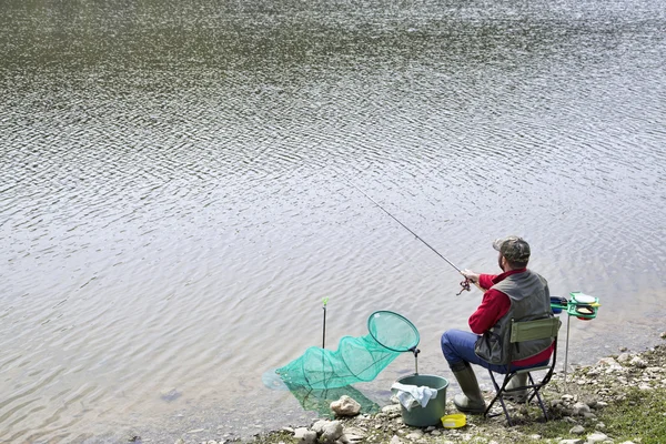 Sports Fisherman With Fishing Equipment Sitting On The Lake Coast And Fishing, Small Waves On The Water Surface — Stock Photo, Image