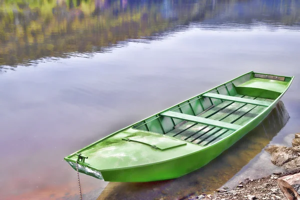 Bateau en bois vert attaché à un petit quai sur le lac calme — Photo