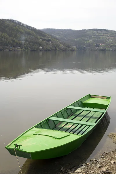 Bateau en bois vert attaché à un petit quai sur le lac calme — Photo