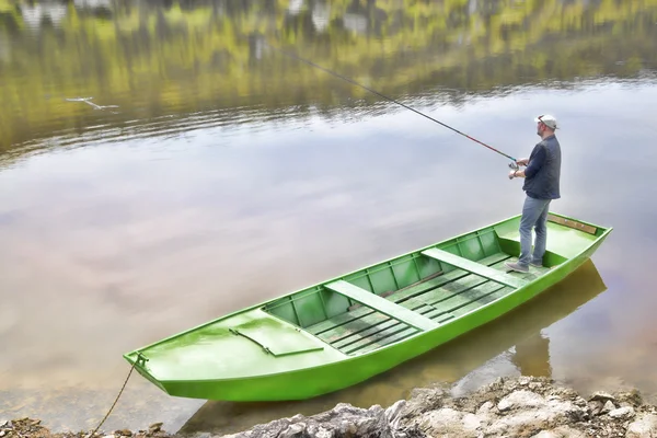 Pescador deportivo sosteniendo caña de pescar y pesca desde el barco verde — Foto de Stock