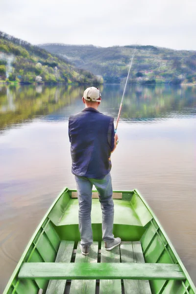 Visão traseira do homem que pesca do barco verde que cambaleia a corda e que espera peixes para tomar uma isca — Fotografia de Stock