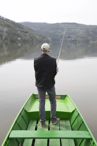 Vista trasera de la pesca del hombre desde el barco verde Cuerda de carrete y esperando peces para morder un cebo — Foto de Stock