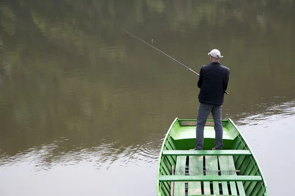 Scène de pêcheur avec son dos vers la caméra de pêche du bateau sur le lac calme — Photo