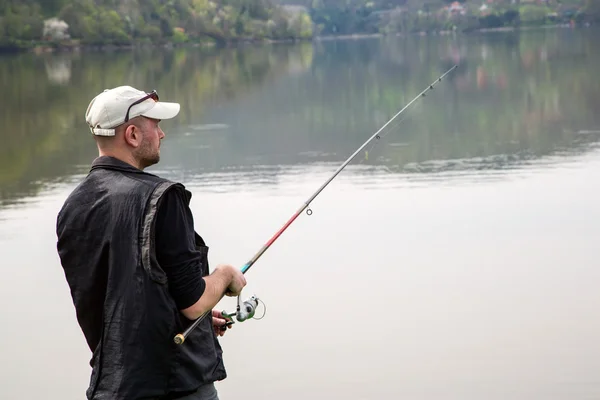 Vista lateral do pescador cambaleando corda e jogando Rod no lago calmo — Fotografia de Stock