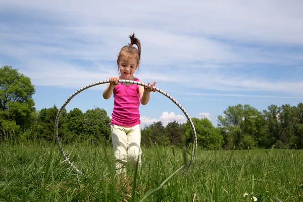 Mosolygós kislány Hula Hoop élvezi a szép tavaszi nap a parkban — Stock Fotó