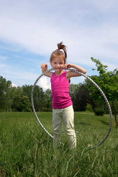 Petite fille souriante avec Hula Hoop Profitant d'une belle journée de printemps dans le parc — Photo