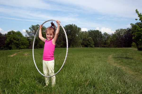 Petite fille souriante avec Hula Hoop Profitant d'une belle journée de printemps dans le parc — Photo
