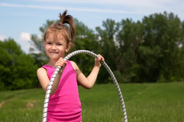 公園内の美しい春の日を楽しんでフラフープ少女の笑みを浮かべてください。 — ストック写真