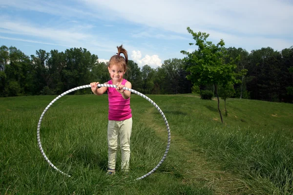 Lächelndes kleines Mädchen mit Hula-Hoop-Reifen genießt schönen Frühlingstag im Park — Stockfoto