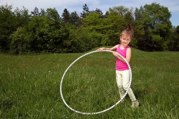 公園内の美しい春の日を楽しんでフラフープ少女の笑みを浮かべてください。 — ストック写真