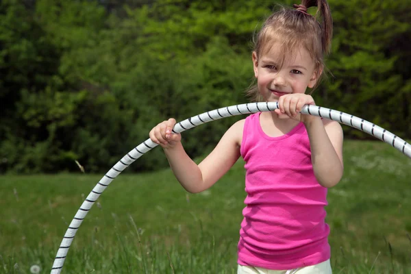 Lächelndes kleines Mädchen mit Hula-Hoop-Reifen genießt schönen Frühlingstag im Park — Stockfoto