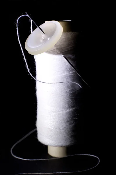 Spool of White Thread with Needle and White Button Isolated on Black — Stock Photo, Image