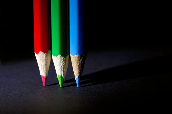 Makro pchnięciu czerwony, zielony i niebieski zaostrzone ołówki kolorowe na czarnym tle — Zdjęcie stockowe