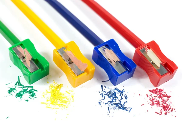 カラフルな鉛筆の削りくずが白で隔離と鉛筆を研ぐ緑、黄色、青、赤の鉛筆削りのマクロ撮影 — ストック写真