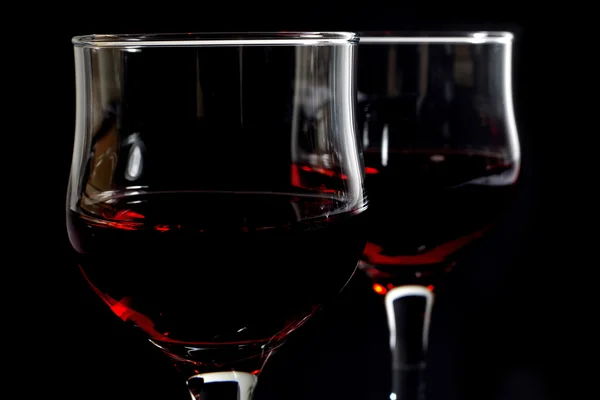 Крупный план двух бокалов, наполненных красным вином на черном — стоковое фото