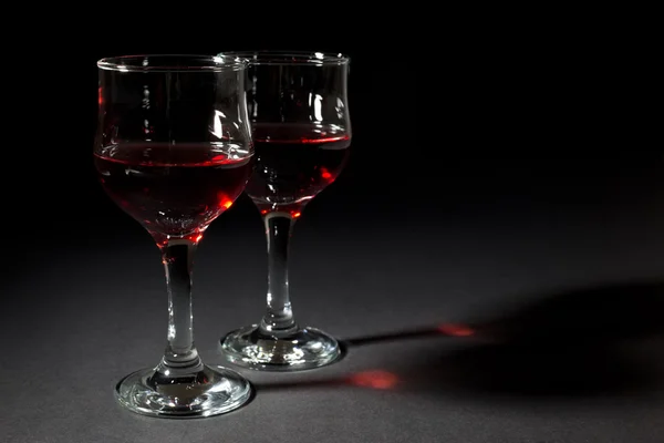 Dois copos de vidro preenchidos com vinho tinto isolado em preto — Fotografia de Stock