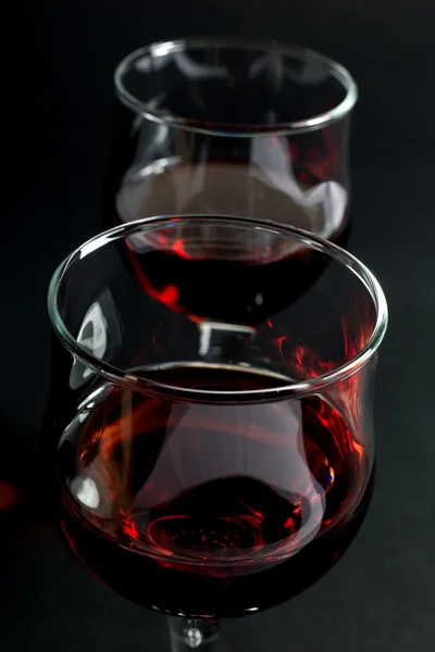Copas de vidrio llenas de vino tinto sobre fondo negro — Foto de Stock