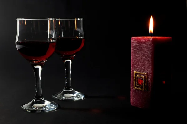 Vela vermelha bonita e duas xícaras de vidro de vinho tinto isolado em preto — Fotografia de Stock