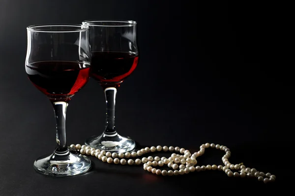 美しい真珠のネックレス、黒に分離された赤ワインの 2 つのガラスのカップ — ストック写真