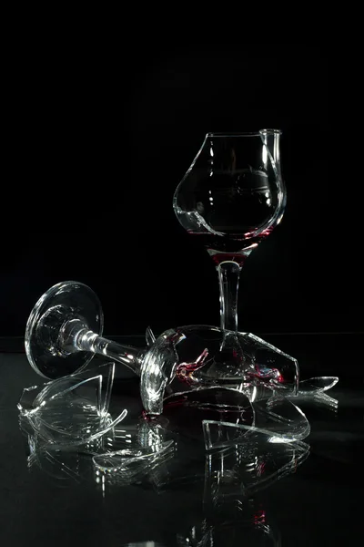 Copas de vidrio roto con reflexión sobre una mesa de vidrio Onr fondo negro — Foto de Stock